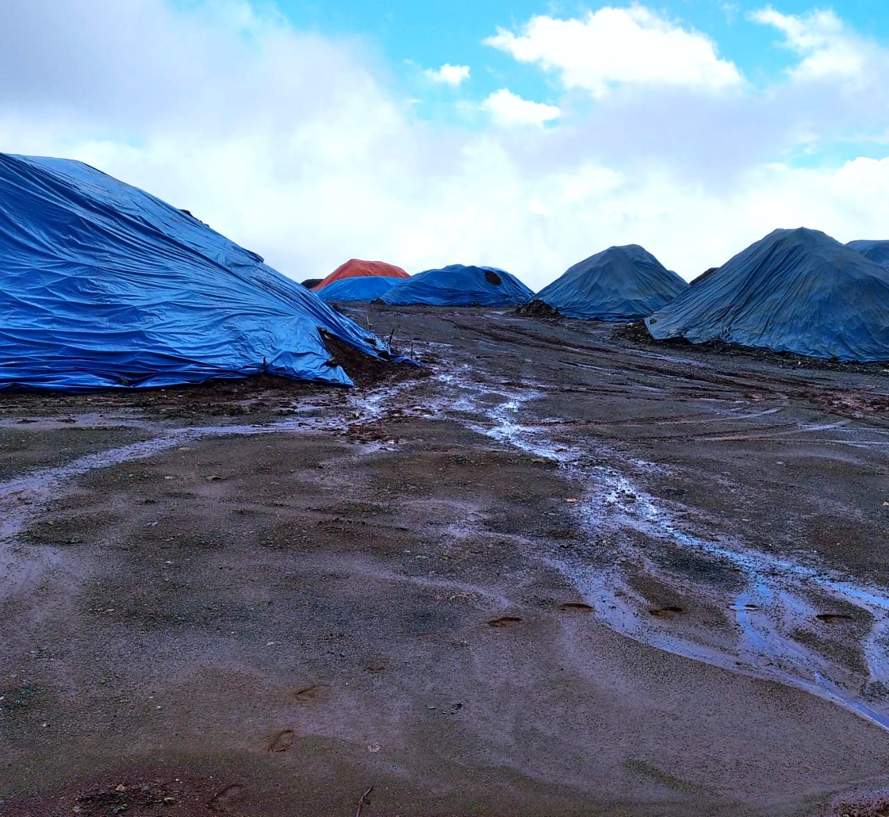 Stockpile tambang tertutup terpal heavy duty biru yang terpapar sinar matahari langsung