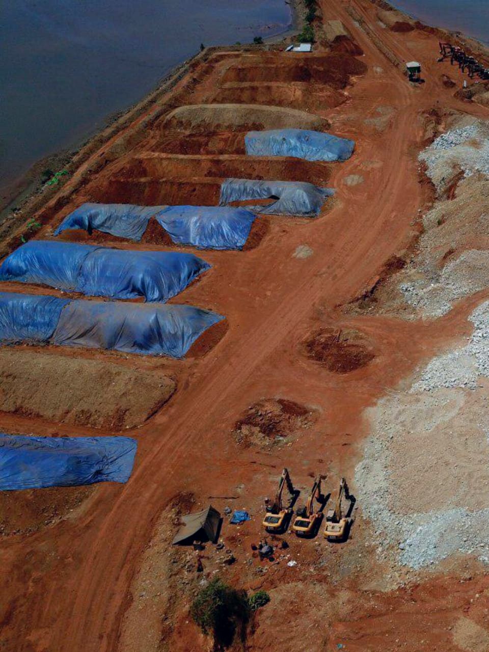 Foto udara area tambang dengan beberapa stockpile yang tertutup terpal